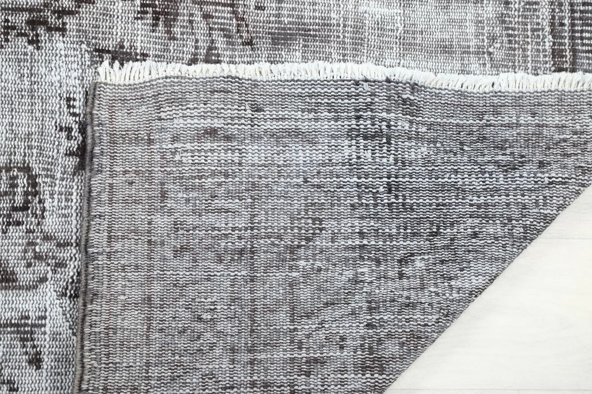 Close-up of the reverse side of the rug, showing the tightly woven cotton foundation and short fringes.