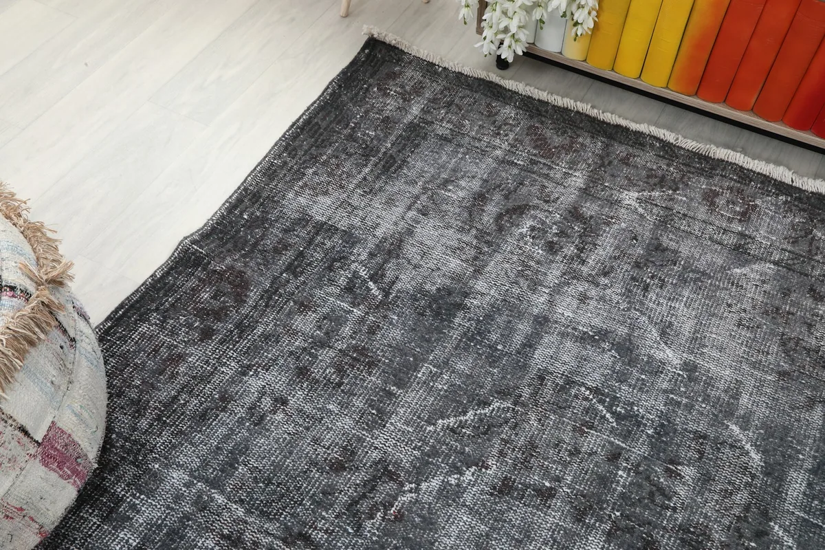 Corner view of the charcoal gray rug, emphasizing its worn texture