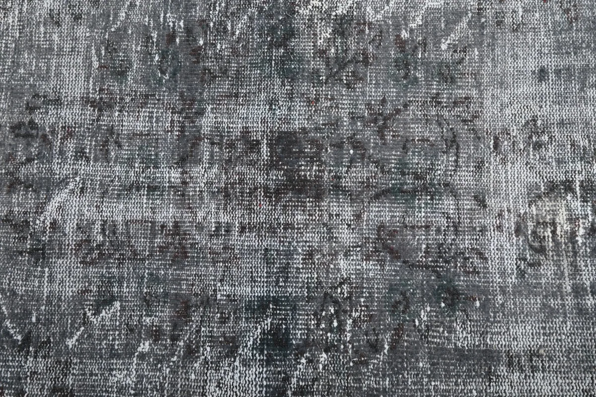 Close-up of the rug's surface, highlighting the distressed wool pile and faded patterns