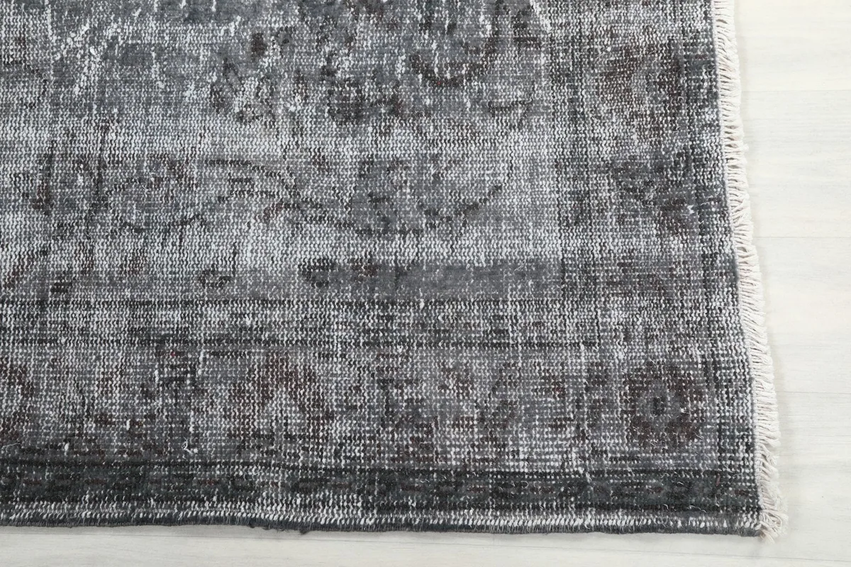Detail of the rug's short fringe and a corner with faint geometric motifs