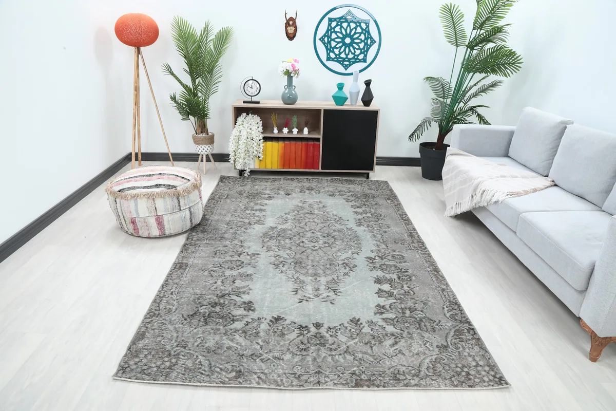 Vintage gray and beige area rug displayed in a living room setting with a light gray sofa