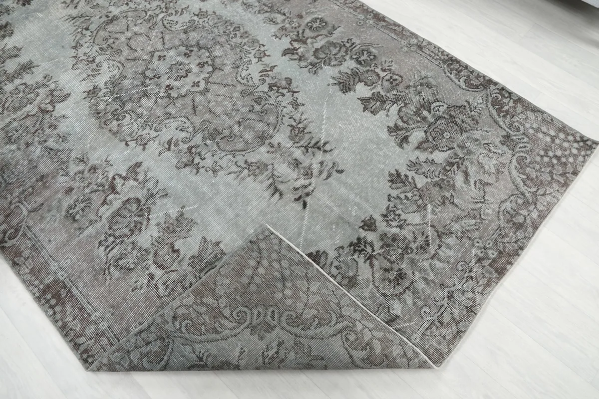 Corner of the rug folded back, revealing the hand-knotted cotton foundation and wool pile