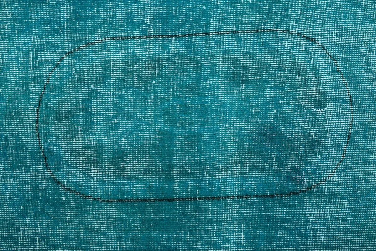 Close-up on the faded medallion outline and distressed wool texture