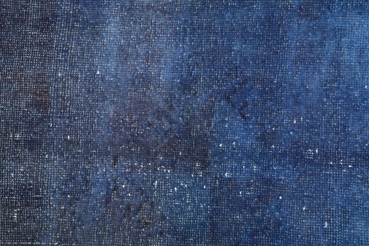 Close-up of the low wool pile, showing faded geometric motifs and wear