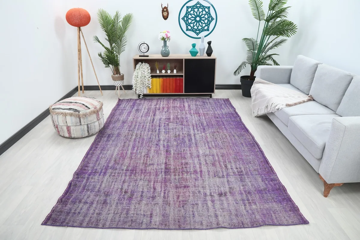 Vintage purple rug displayed in a modern living room setting with sofa and decor