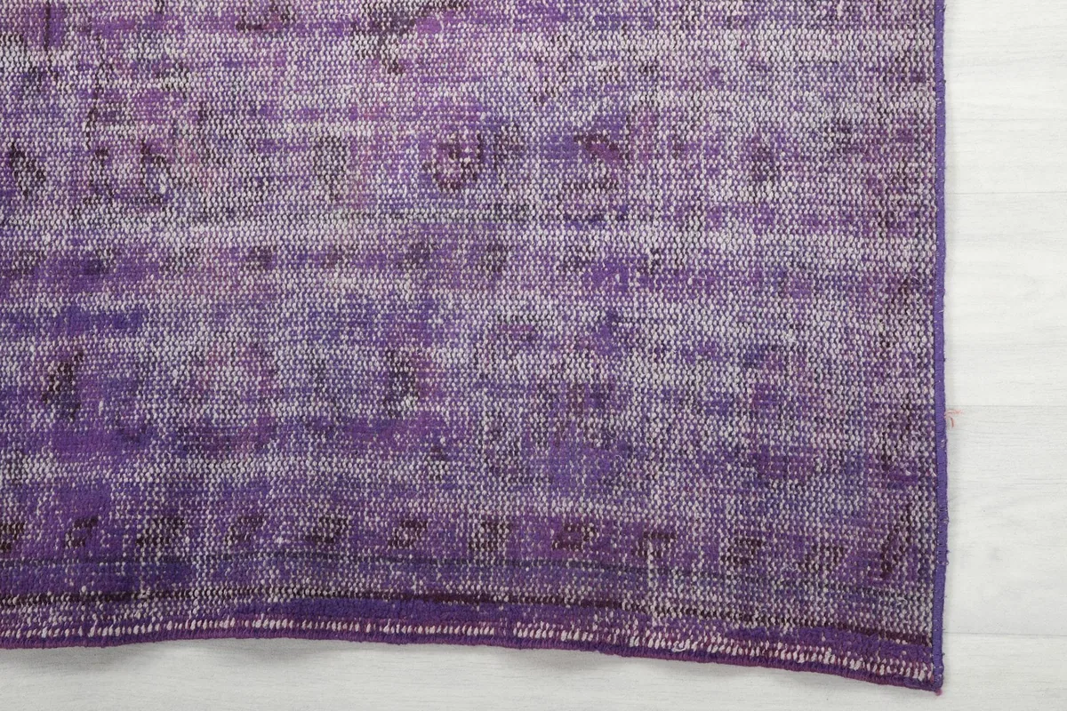 Detailed view of the purple rug's edge, highlighting the faded color and hand-knotted structure