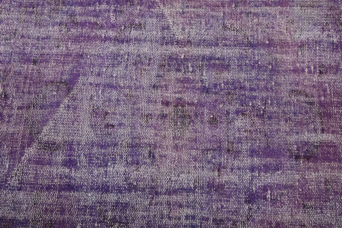 Close-up of the rug's central area, revealing faded geometric motifs and distressed wool pile