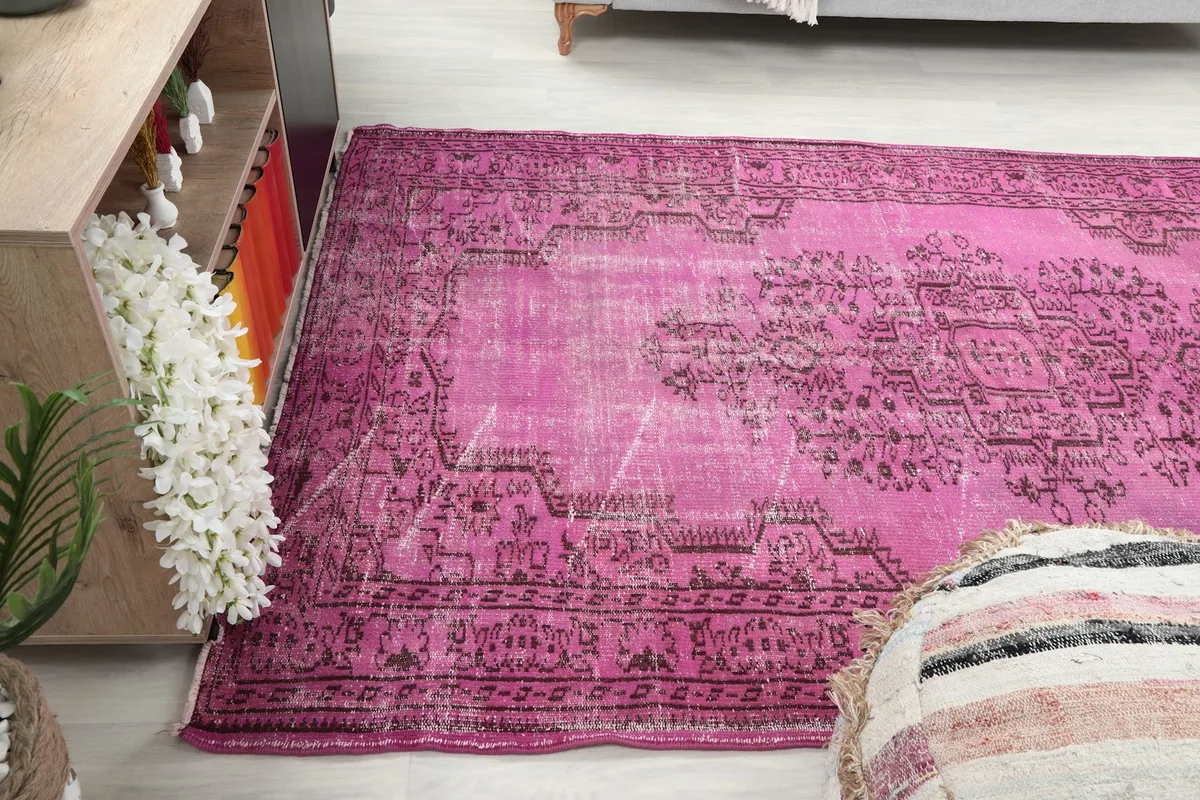 Side angle view of the pink rug on the floor, showing its placement in a room