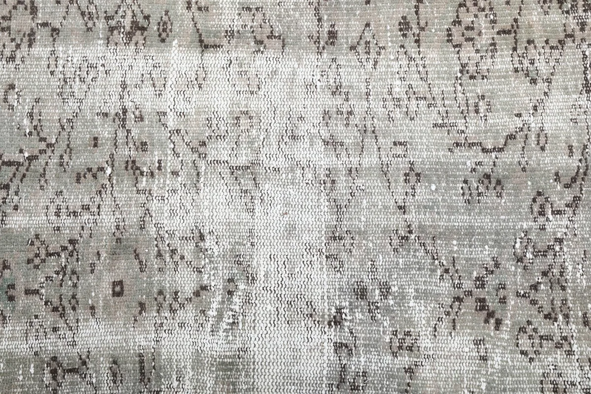 Close-up of the rug's low pile and intricate charcoal floral and geometric designs