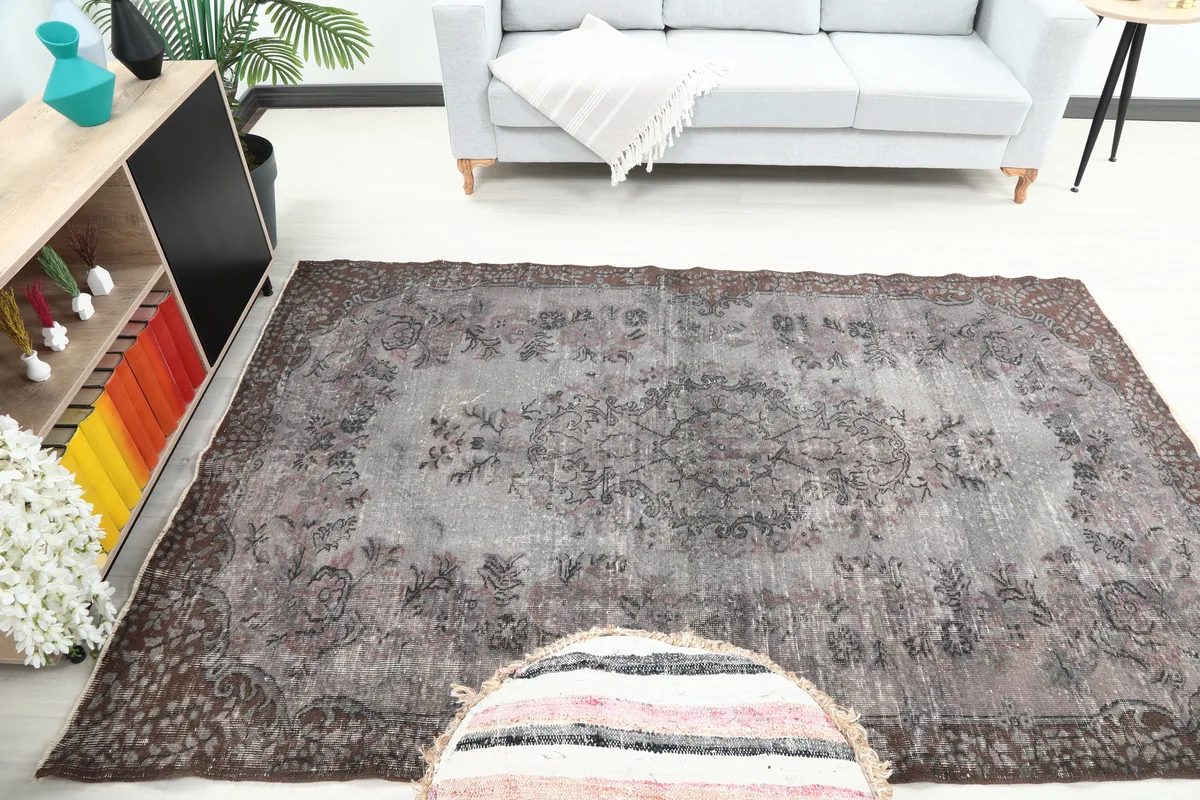 Faded Charcoal Floral Anatolian Rug in a room with a sofa and pouf