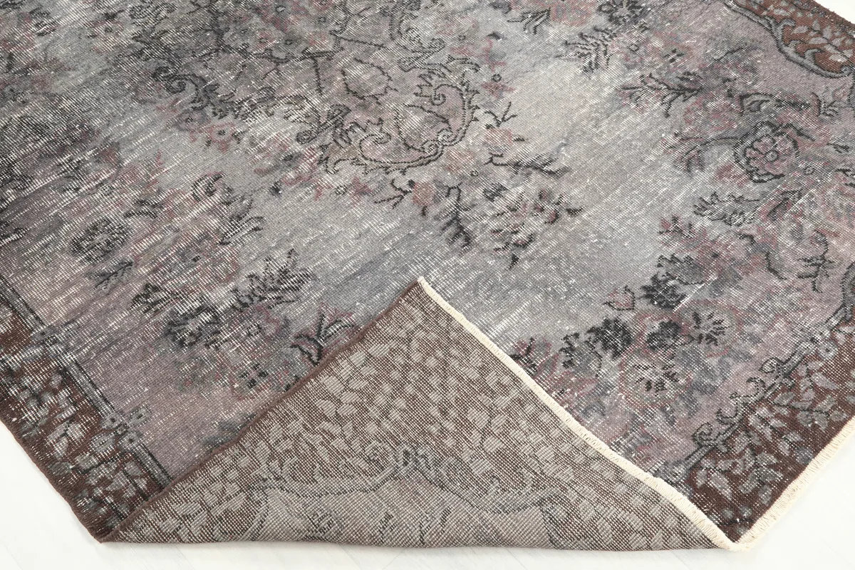Corner of the rug folded to show the hand-knotted back and fringe