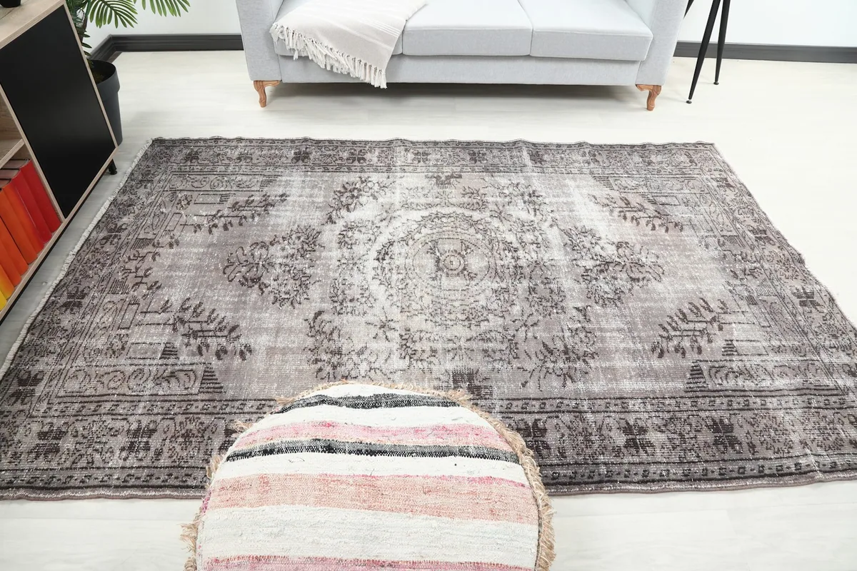 Full room view of the vintage rug with a pouf in the foreground