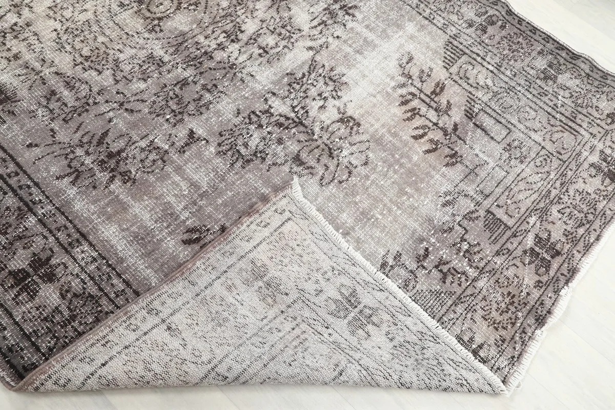 Corner of the rug folded back to show the cotton foundation and hand-knotted reverse
