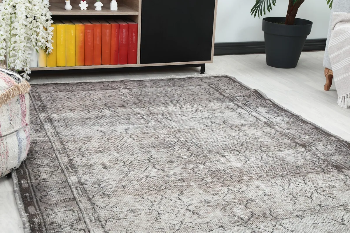 Close-up angle view of the gray rug's pattern and texture next to a bookshelf