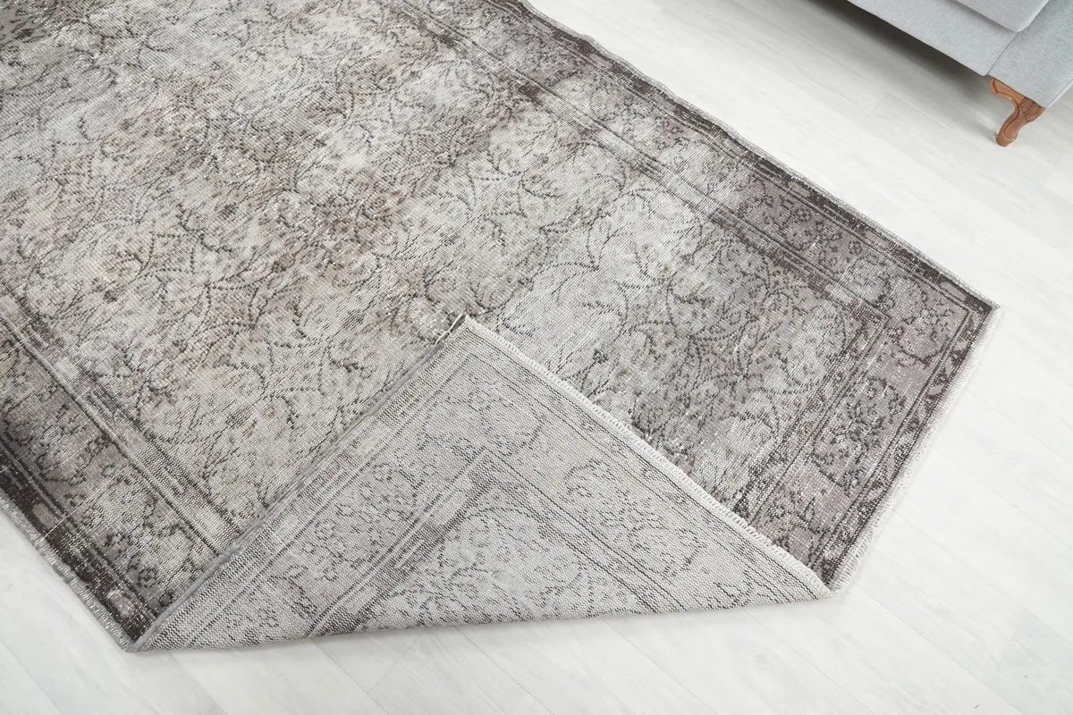 Corner of the rug folded back, revealing the hand-knotted wool pile and cotton foundation