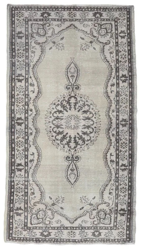 Overhead view of the full beige and charcoal vintage Anatolian rug on a white background