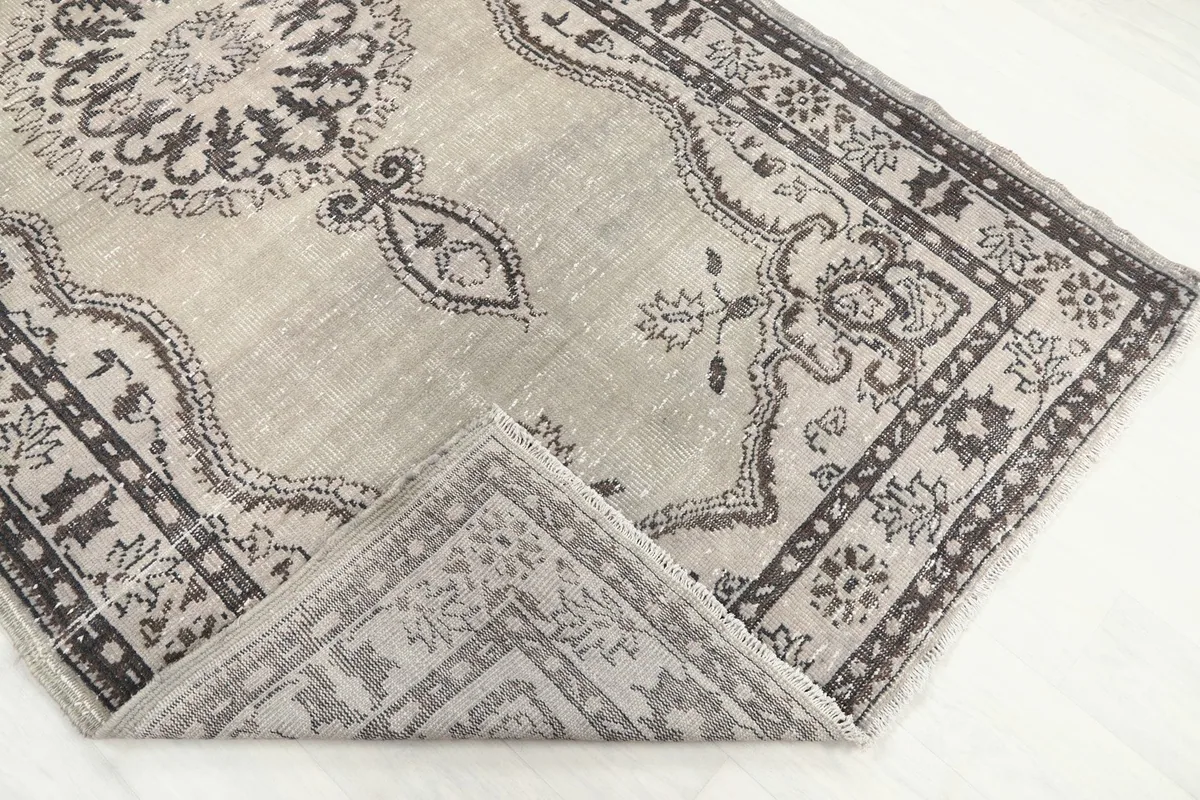 Corner of the rug folded back to show the pile and foundation