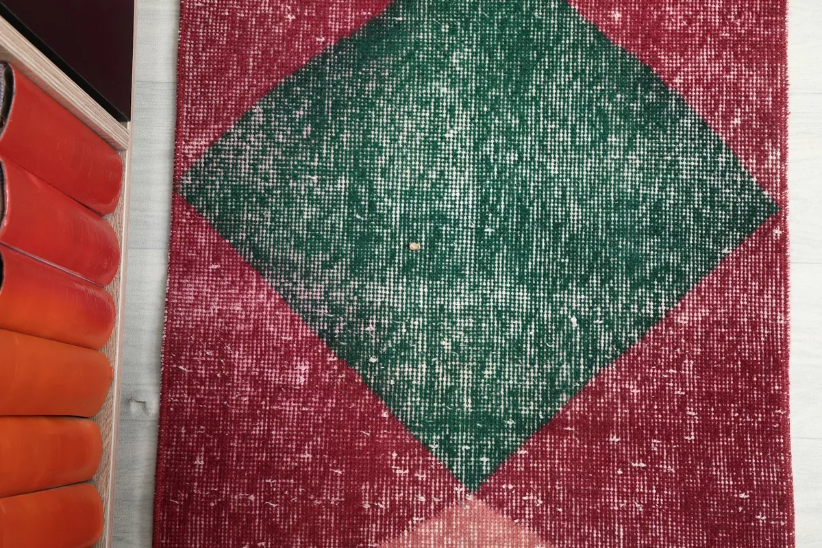 Detail shot of the central green diamond motif on the vintage runner rug.