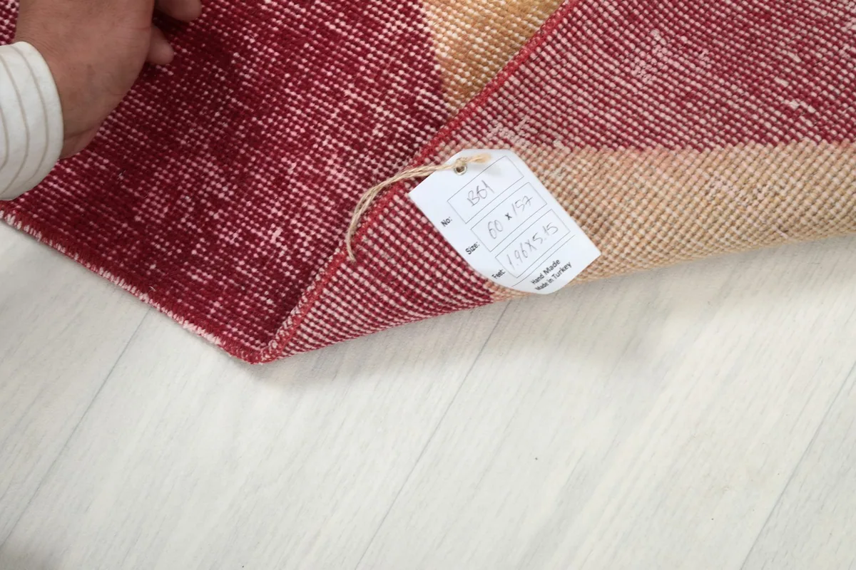 Hand holding the product tag attached to the corner of the runner rug, displaying size information.