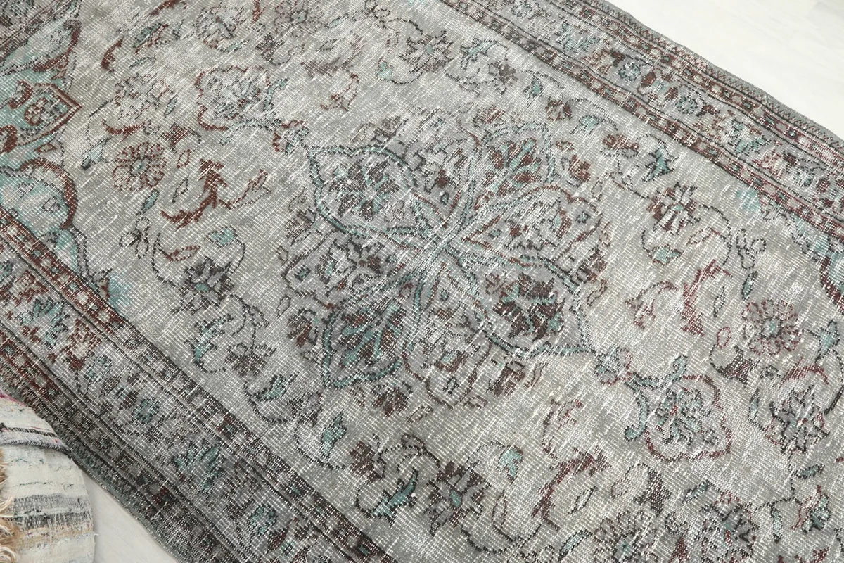 Overhead angle view focusing on the central medallion and surrounding floral motifs of the rug