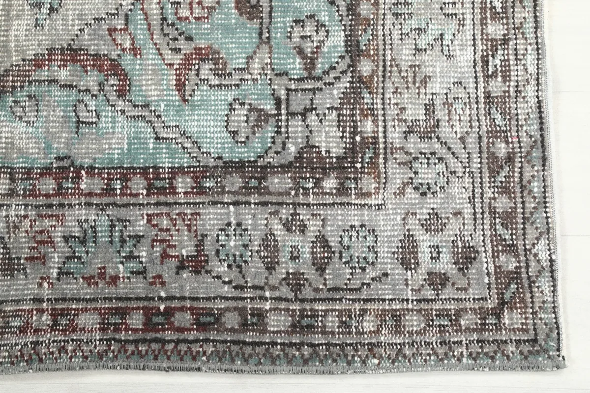 Detailed corner view of the gray blue rug showing the intricate border design and colors