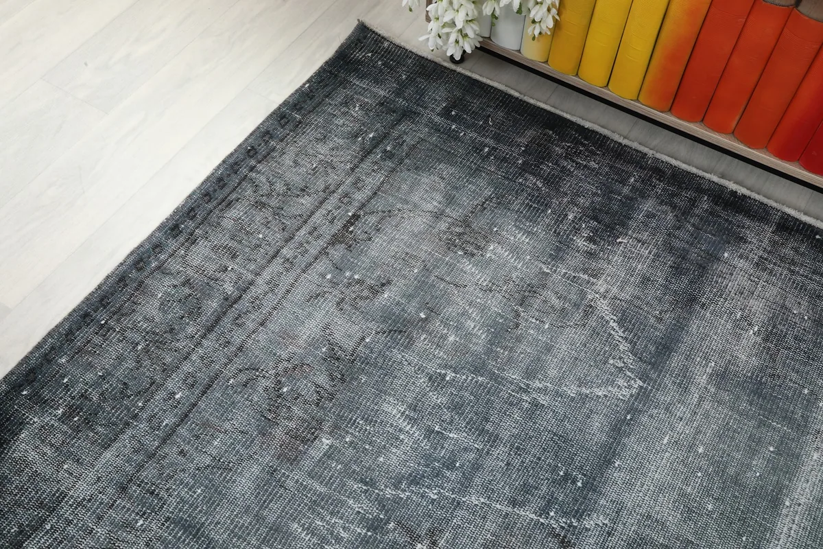 Corner view of the vintage rug, showing the blend of charcoal and gray with subtle patterns