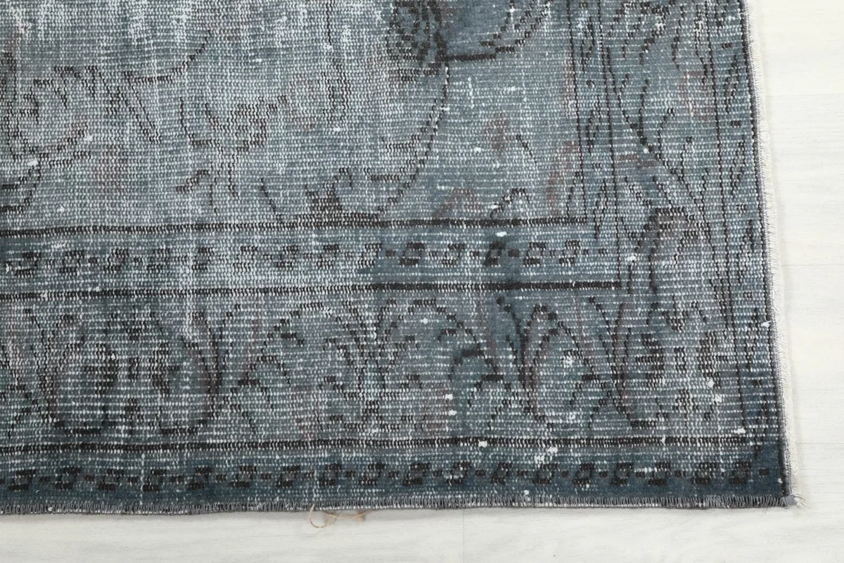 Detail of the rug's border, revealing faded geometric patterns and texture