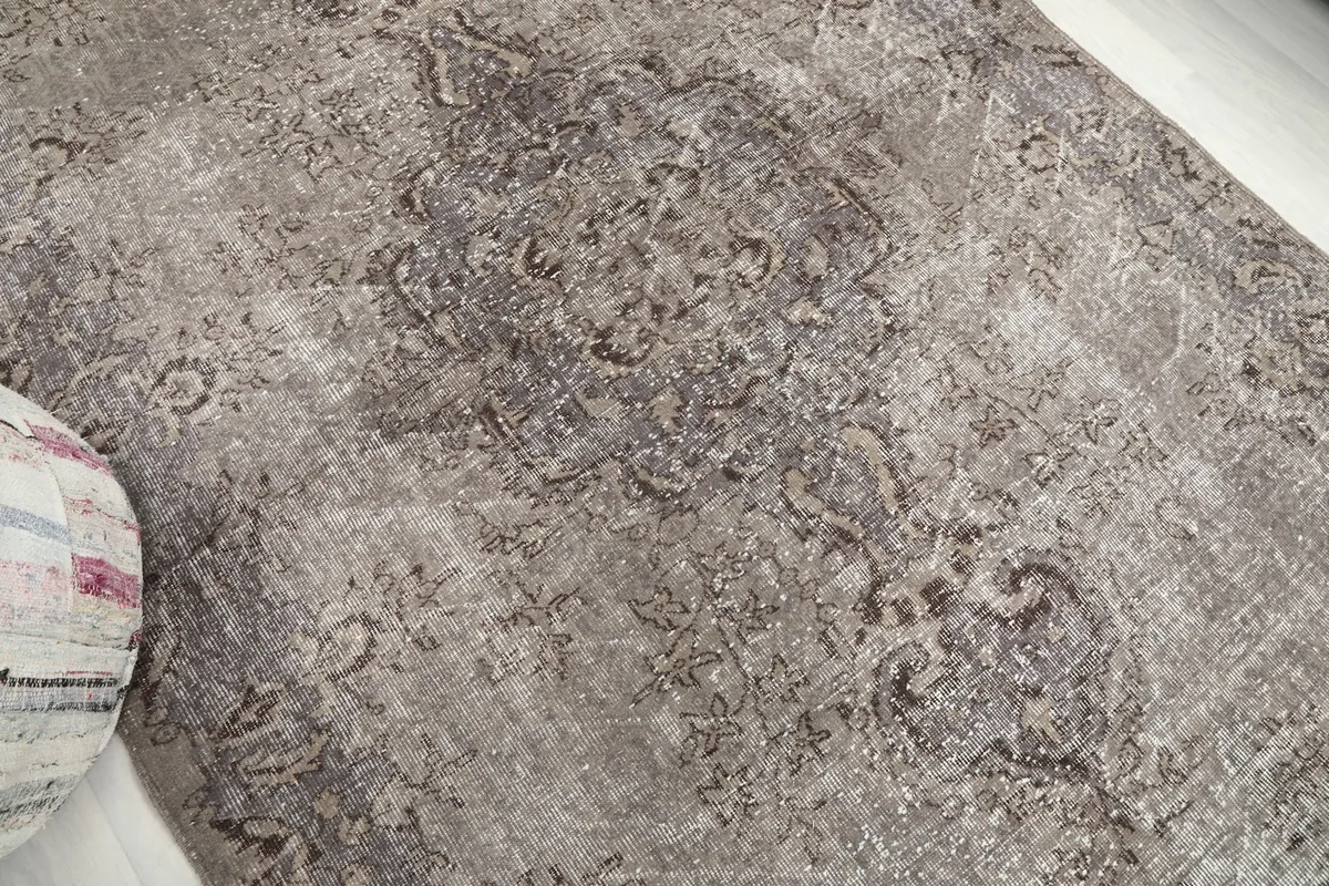 Close-up of the vintage rug's surface, showing the subtle color variations and intricate motifs