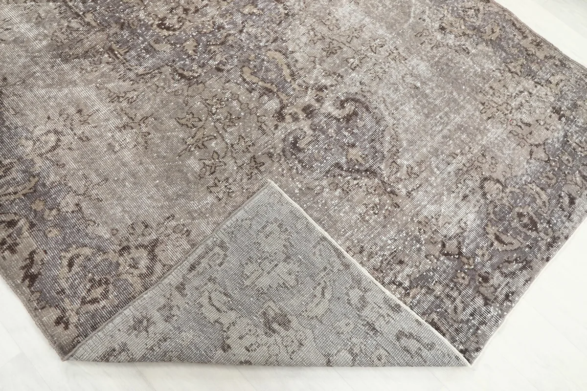 Corner of the rug folded back, showing the cotton foundation and reverse side of the knots