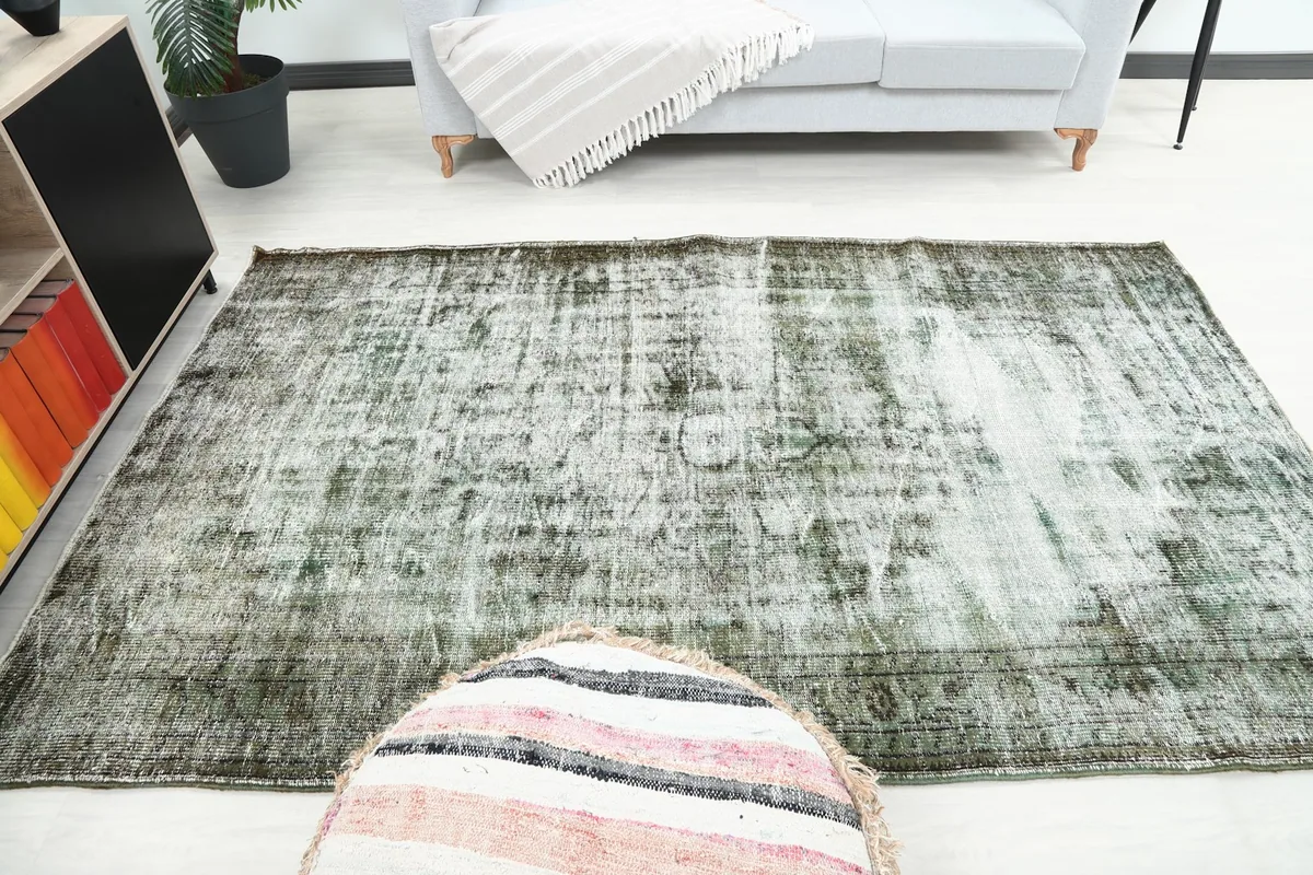 View of the rug in a living space, from above a striped pouf, showing its integration with room elements.