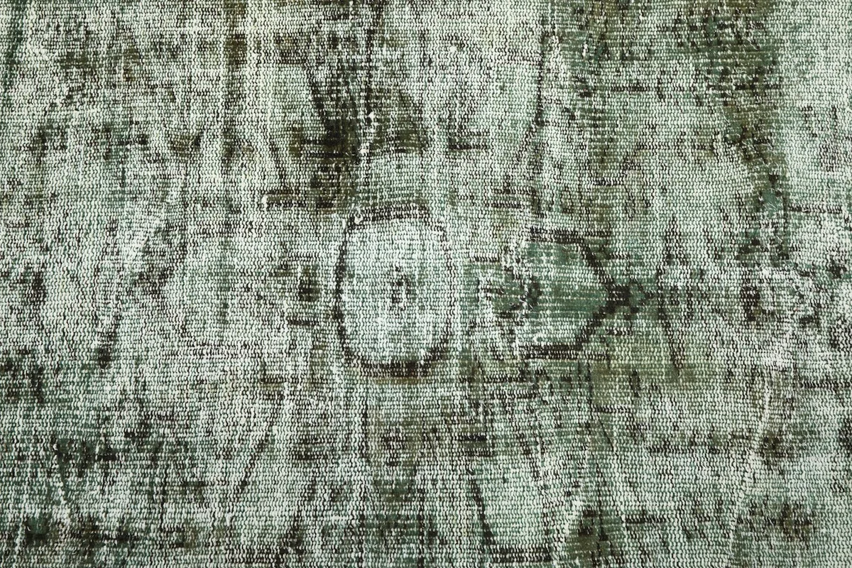 Detailed view of the rug's surface, showing remnants of geometric motifs and the distressed wool pile.
