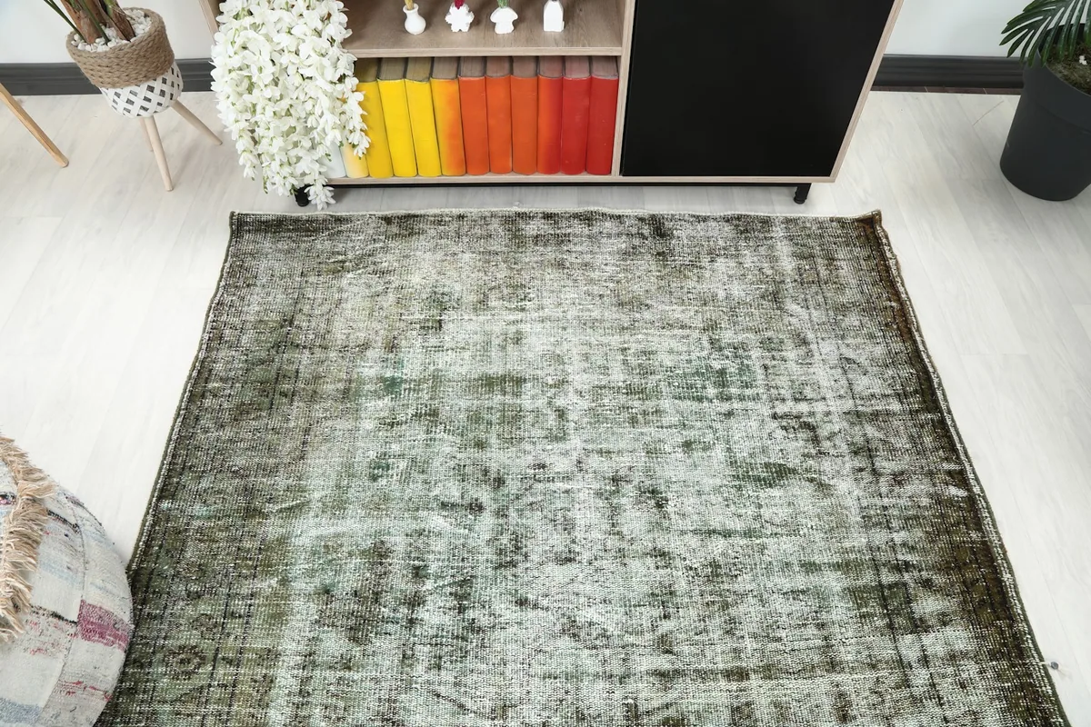 Overhead view of the rug laid out in a room, showing its overall distressed appearance and color distribution.