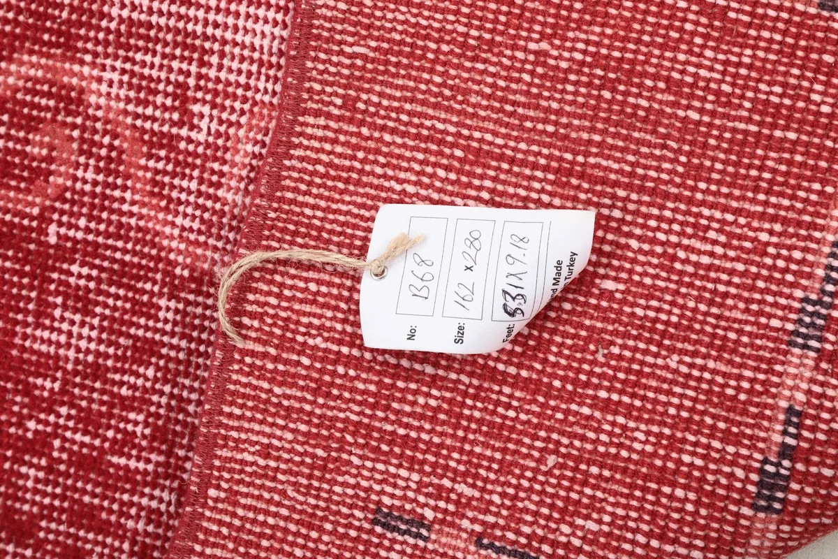 Close-up of the rug's reverse side with a tag showing the dimensions and product details.