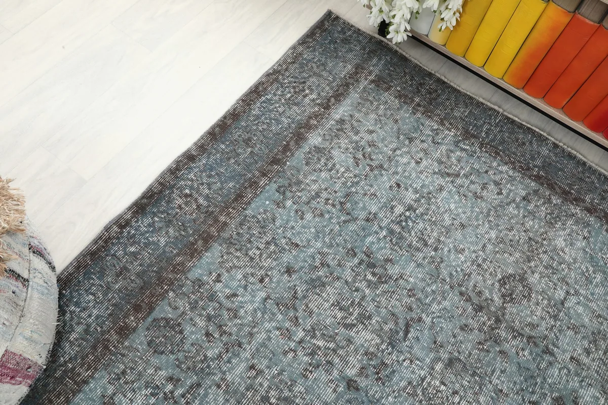 Corner detail of the blue rug, showing the faded brown border and field texture