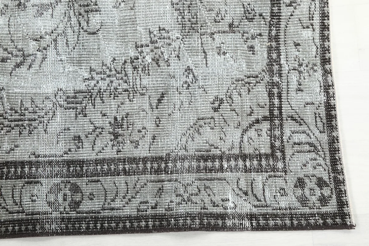 Close-up detail of the charcoal border and corner motif of the vintage rug
