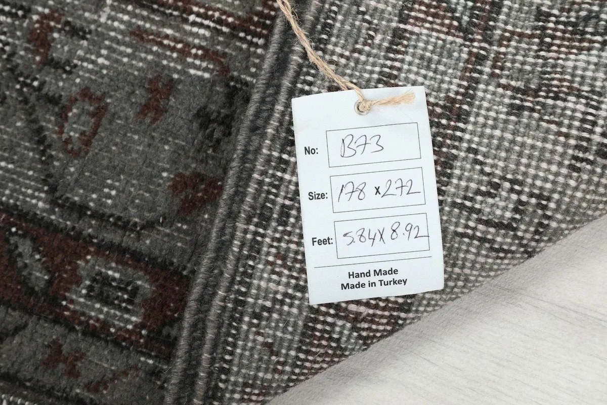 Tag showing the rug's unique number, size in centimeters, and feet, confirming its handmade origin.