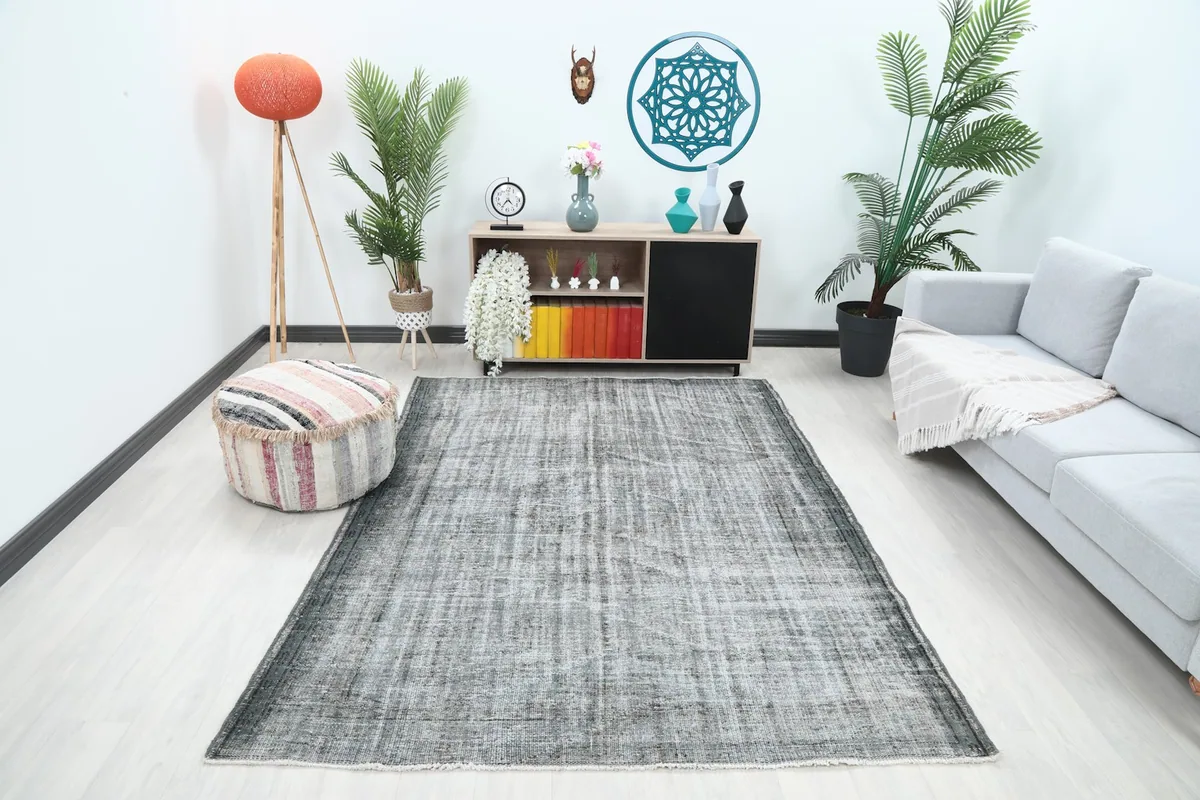 Gray vintage rug displayed in a bright living room setup with a sofa and plants