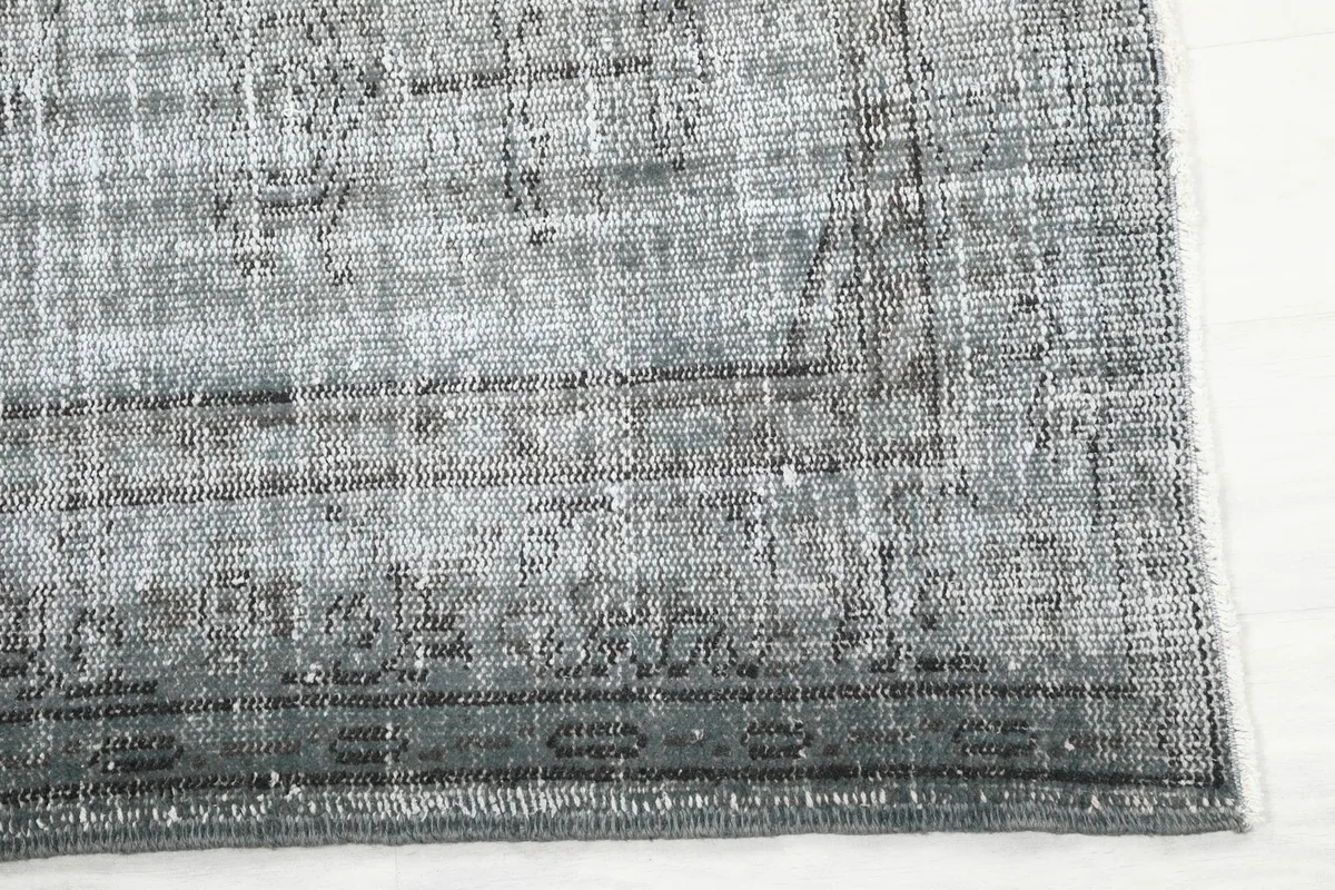Detailed view of the charcoal border and subtle geometric motifs on the vintage rug