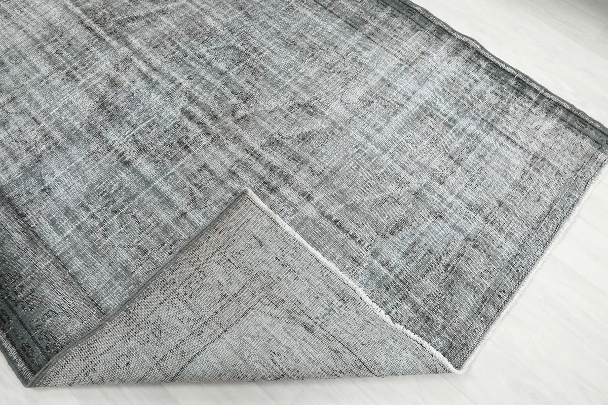 Corner of the rug folded back, revealing the hand-knotted wool pile and cotton foundation