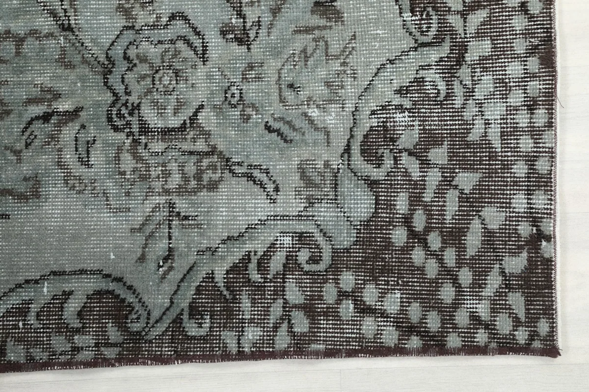Detailed view of the charcoal border pattern against the blue gray field