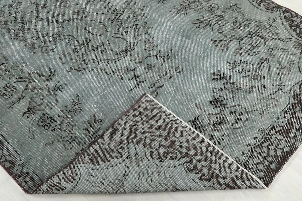 Folded corner of the rug revealing the cotton foundation and reverse side of the pattern