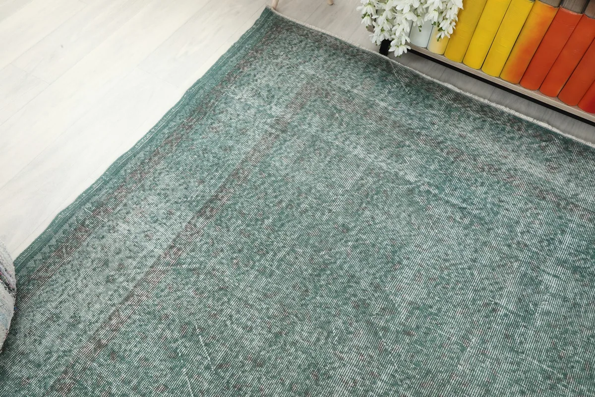 Corner view of the rug, capturing the interaction of green and gray tones in the distressed finish.