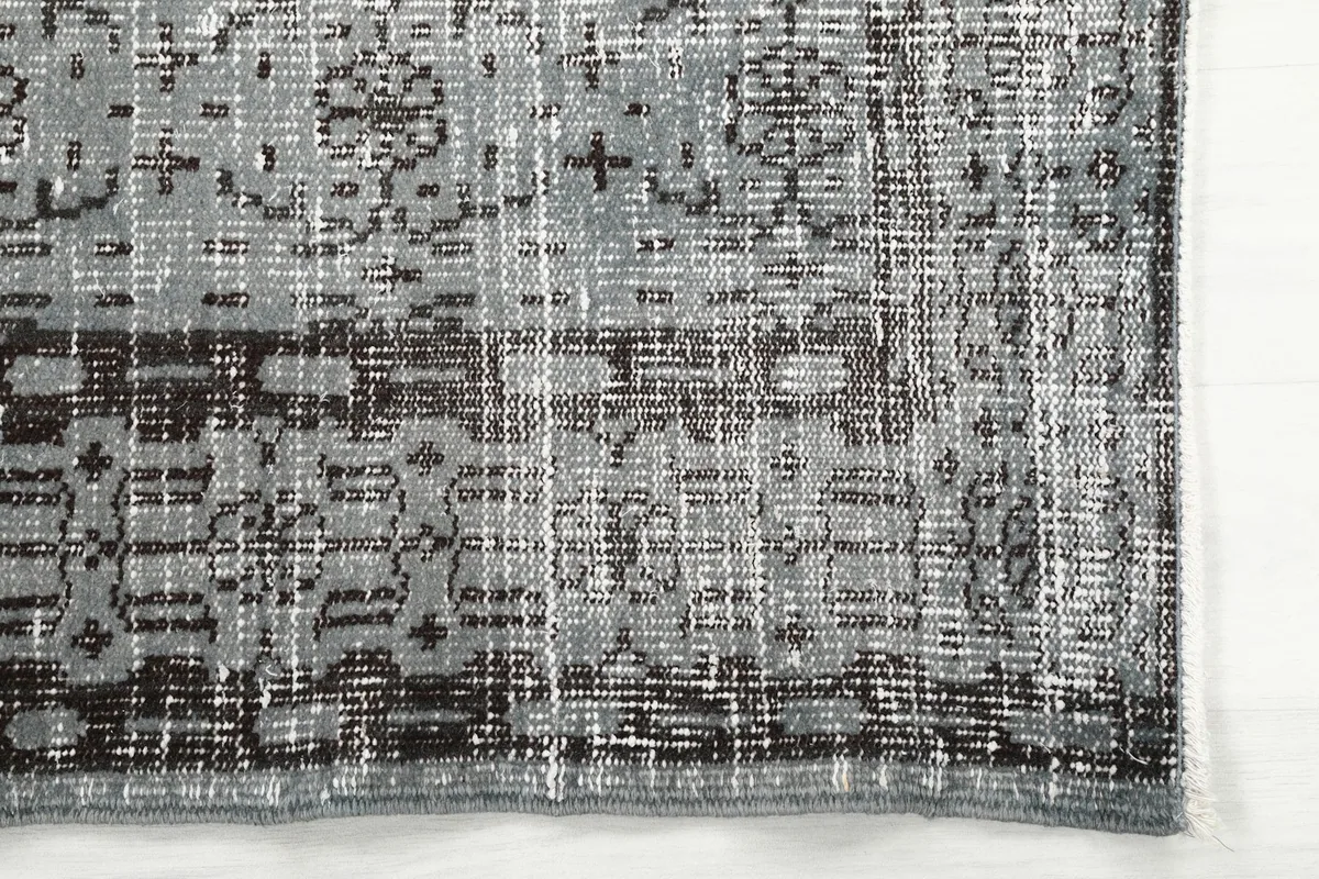 Close-up of the rug's border with distressed charcoal and gray tones