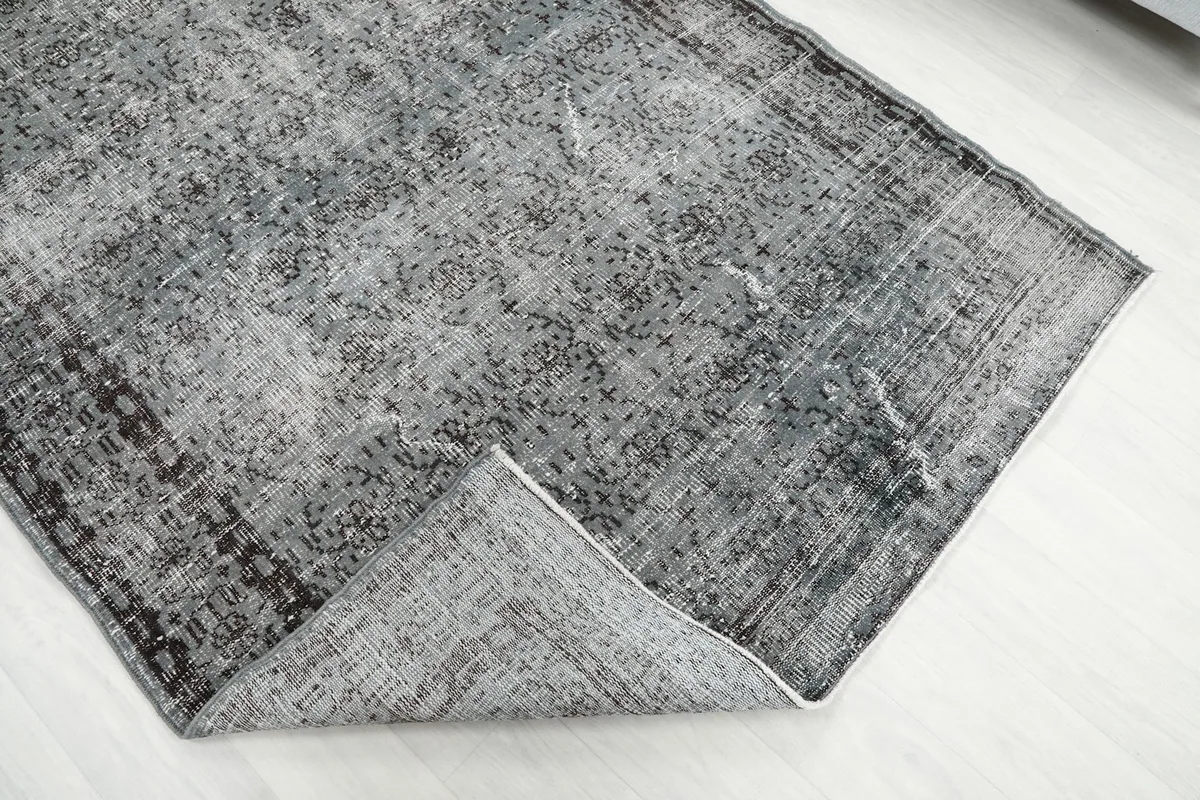 Corner of the rug folded back to show the reverse side and foundation