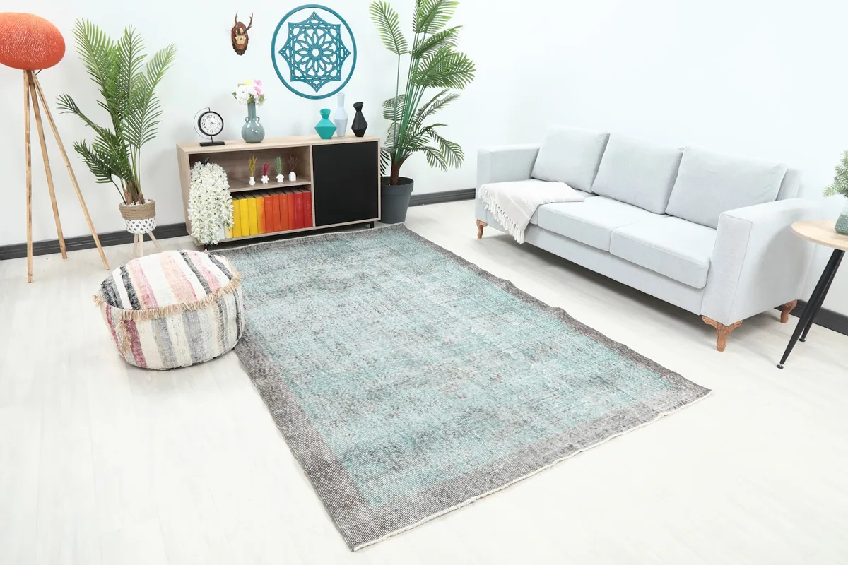 Angled view of the rug in a living room, showing its placement in front of a sofa and a striped pouf.