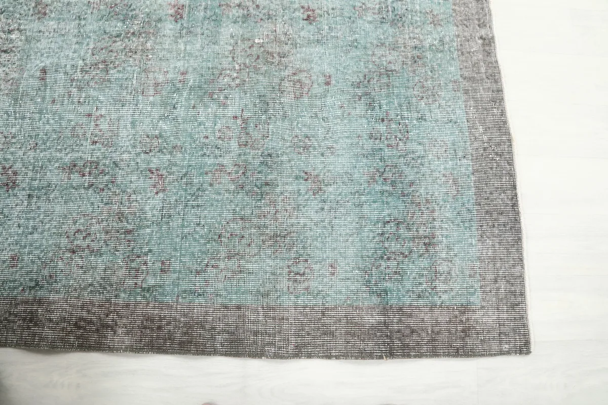 Corner detail of the rug showing the faded blue center transitioning into the gray border.