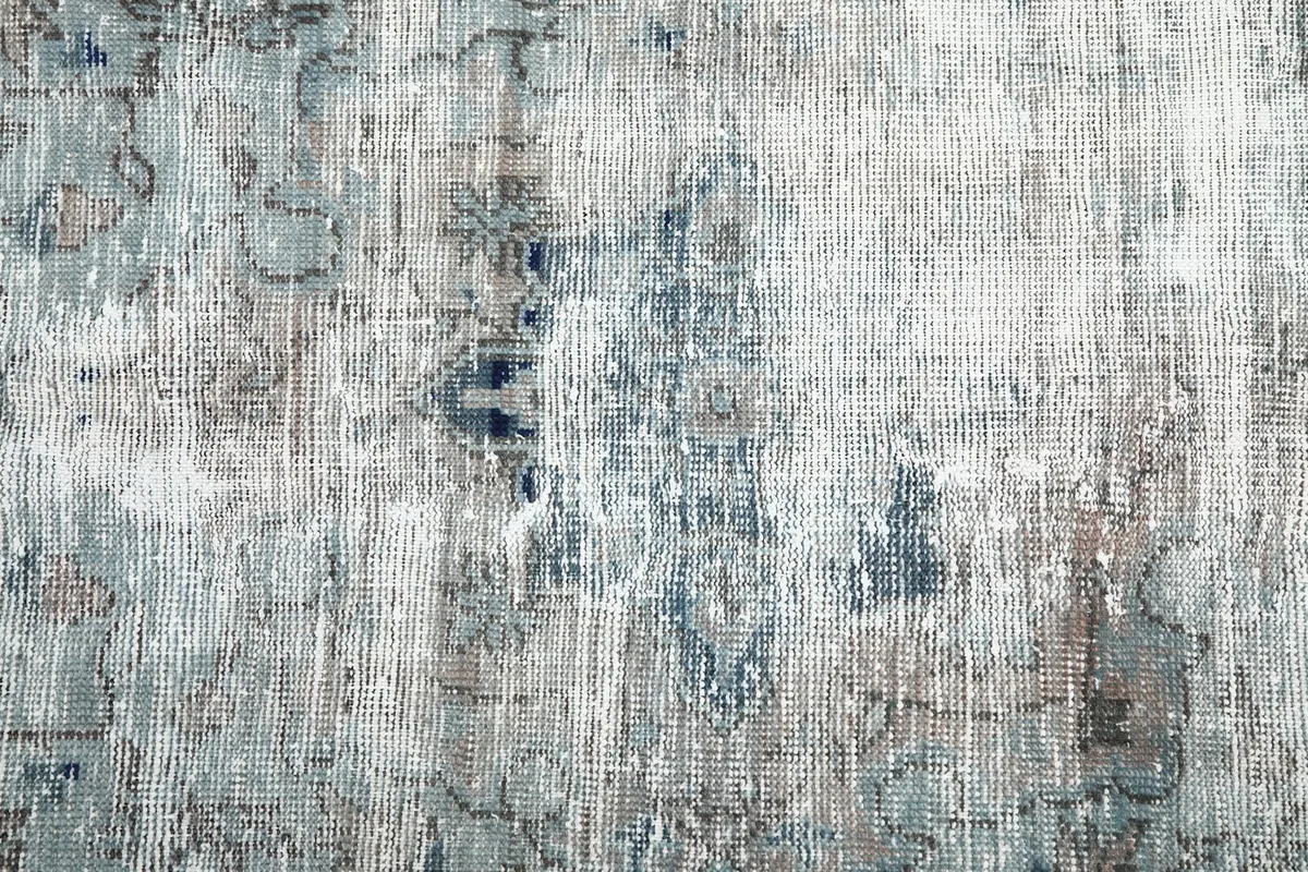 Close-up on the faded floral and geometric motifs in the rug's field