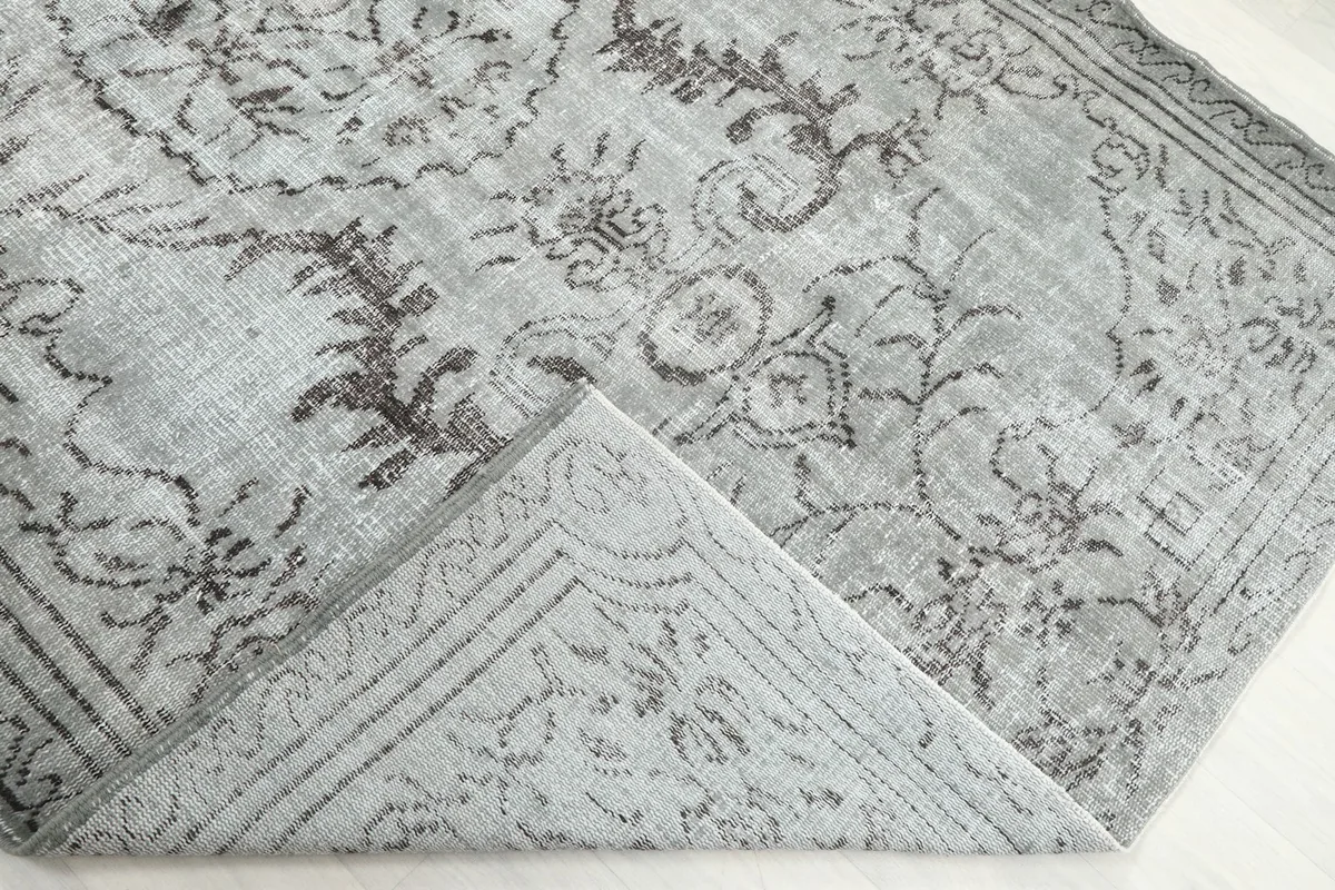 Folded corner of the rug, revealing the back and the hand-knotted construction.
