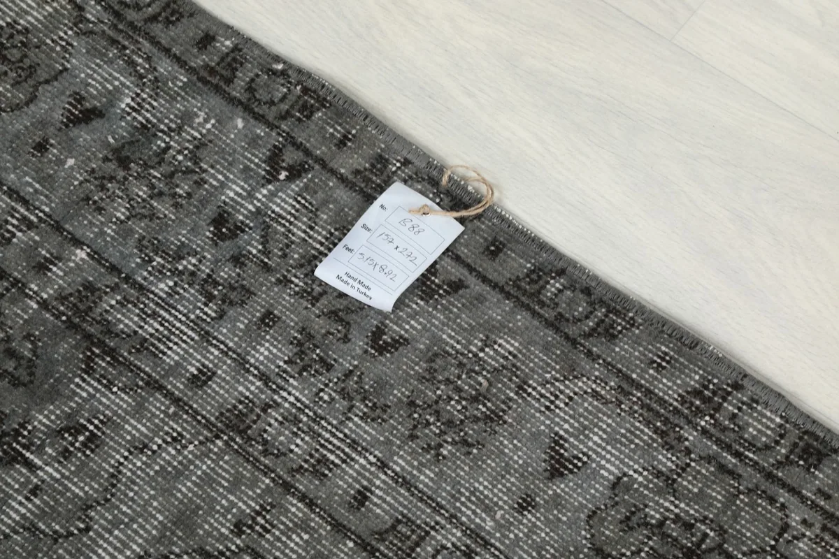 Detail of the rug's surface with an attached product tag, showing texture and color