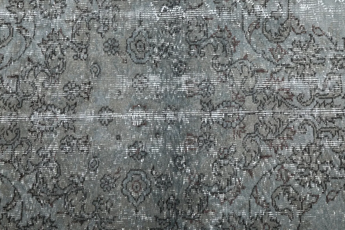 Detailed view of the distressed blue and gray wool pile and floral patterns